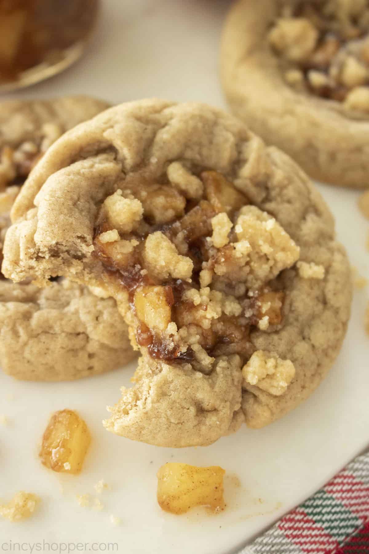 Close up of bitten apple cookie. Showing the apple pie filling and crumb topping.
