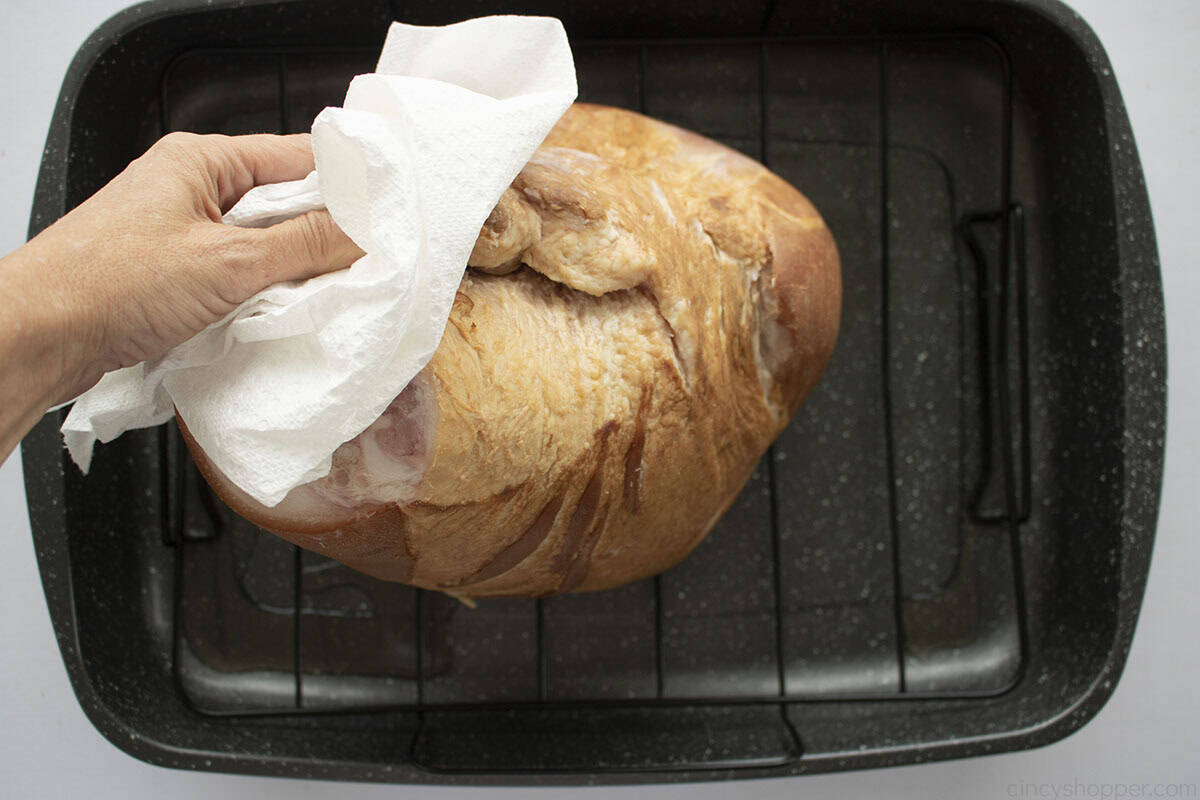 Patting ham dry with a paper towel.