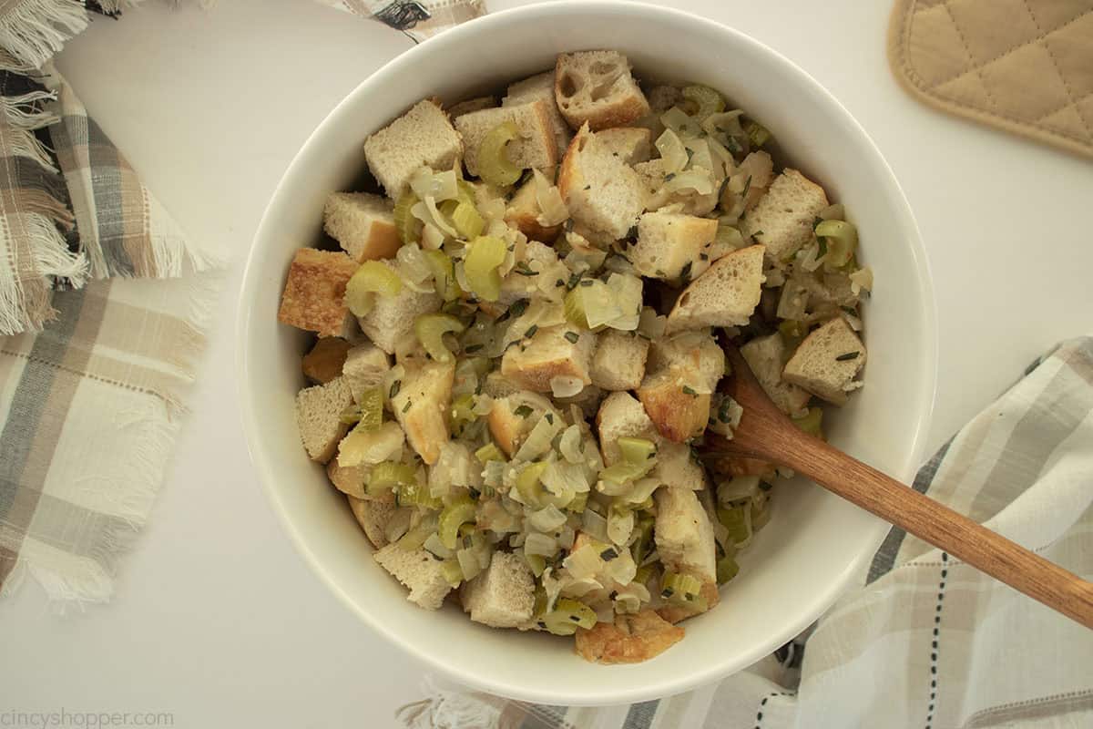 Large bowl with bread cubes and butter, herb and veggie mixture.