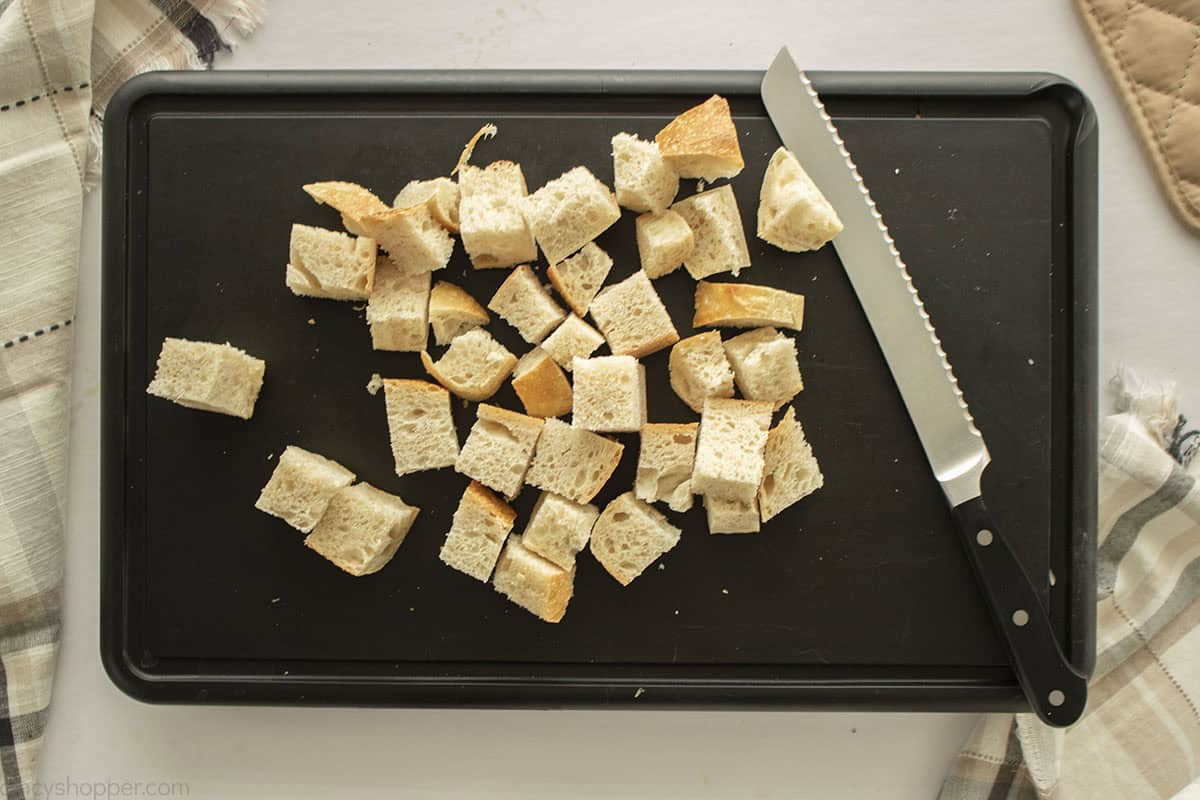 Cubed stale bread on a cutting board.