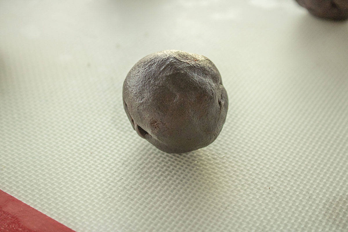 Chocolate peppermint cookie dough ball on baking sheet.