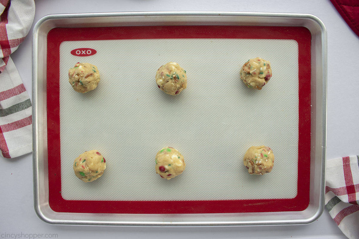 Raw cookie balls on a sheet pan.
