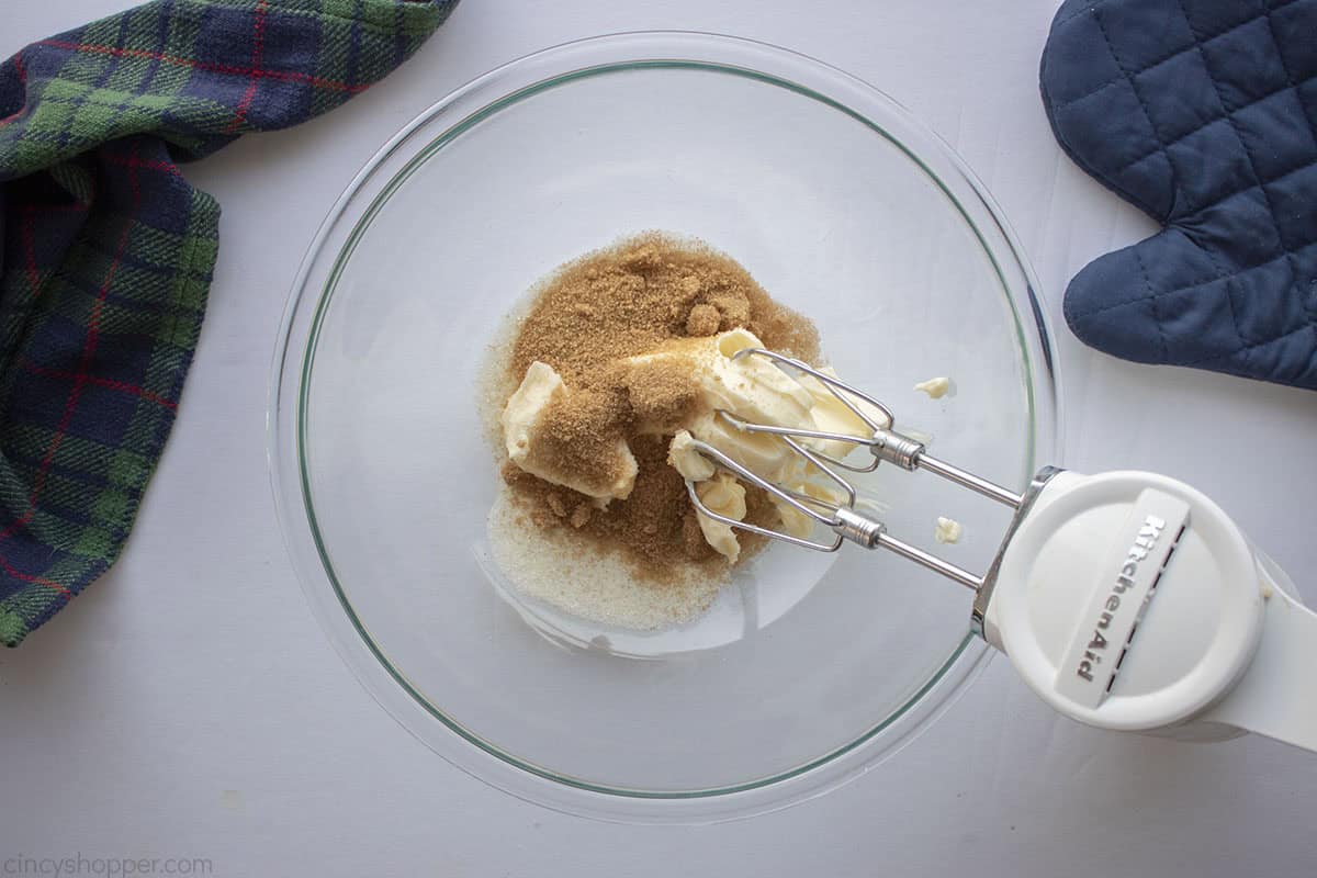 Butter and sugars in a clear mixing bowl with hand mixer.