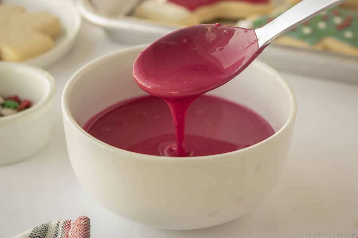 Spoon drizzling red icing.