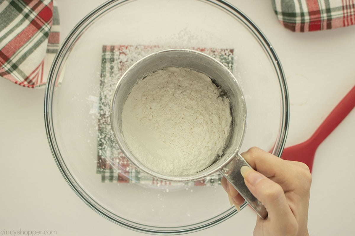Sifting powdered sugar into a mixing bowl.