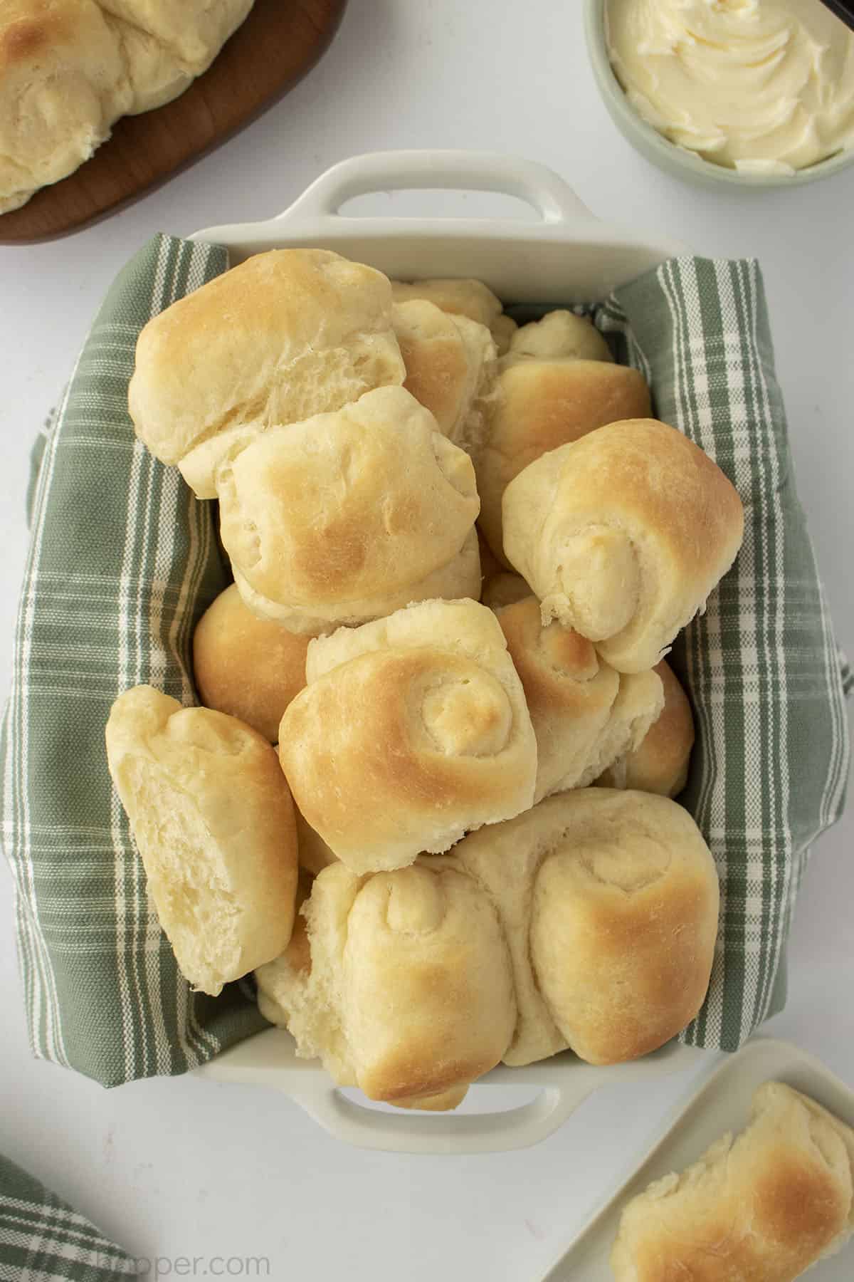 Stack of dinner rolls in a napkin lined dish.