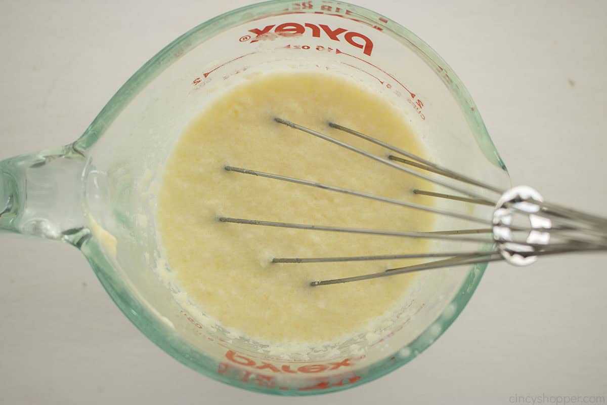 Milk and butter mixture for potatoes in a measuring cup with a whisk.