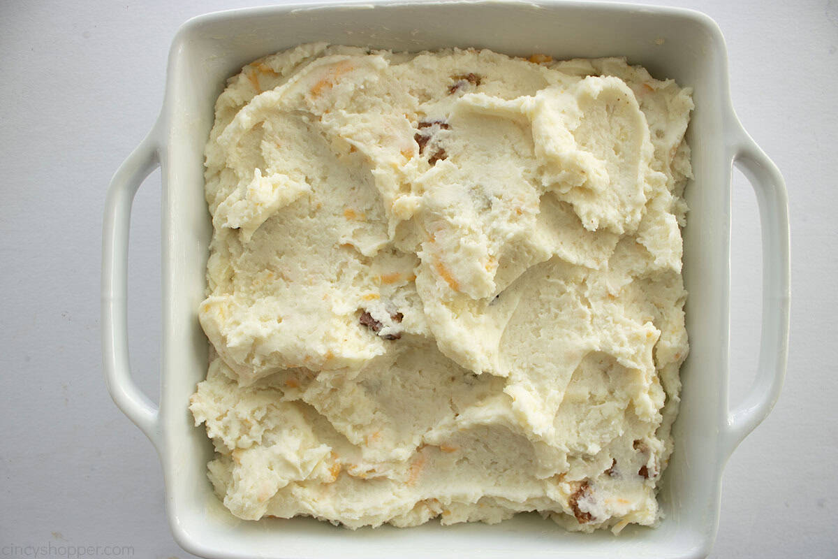 Mashed potato mixture added to white baking dish.