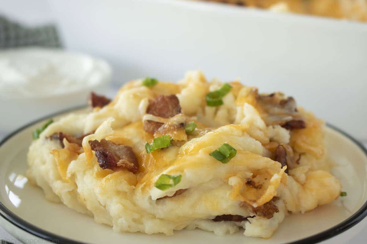 Mashed potatoes casserole with bacon , cheese and green onions on top.