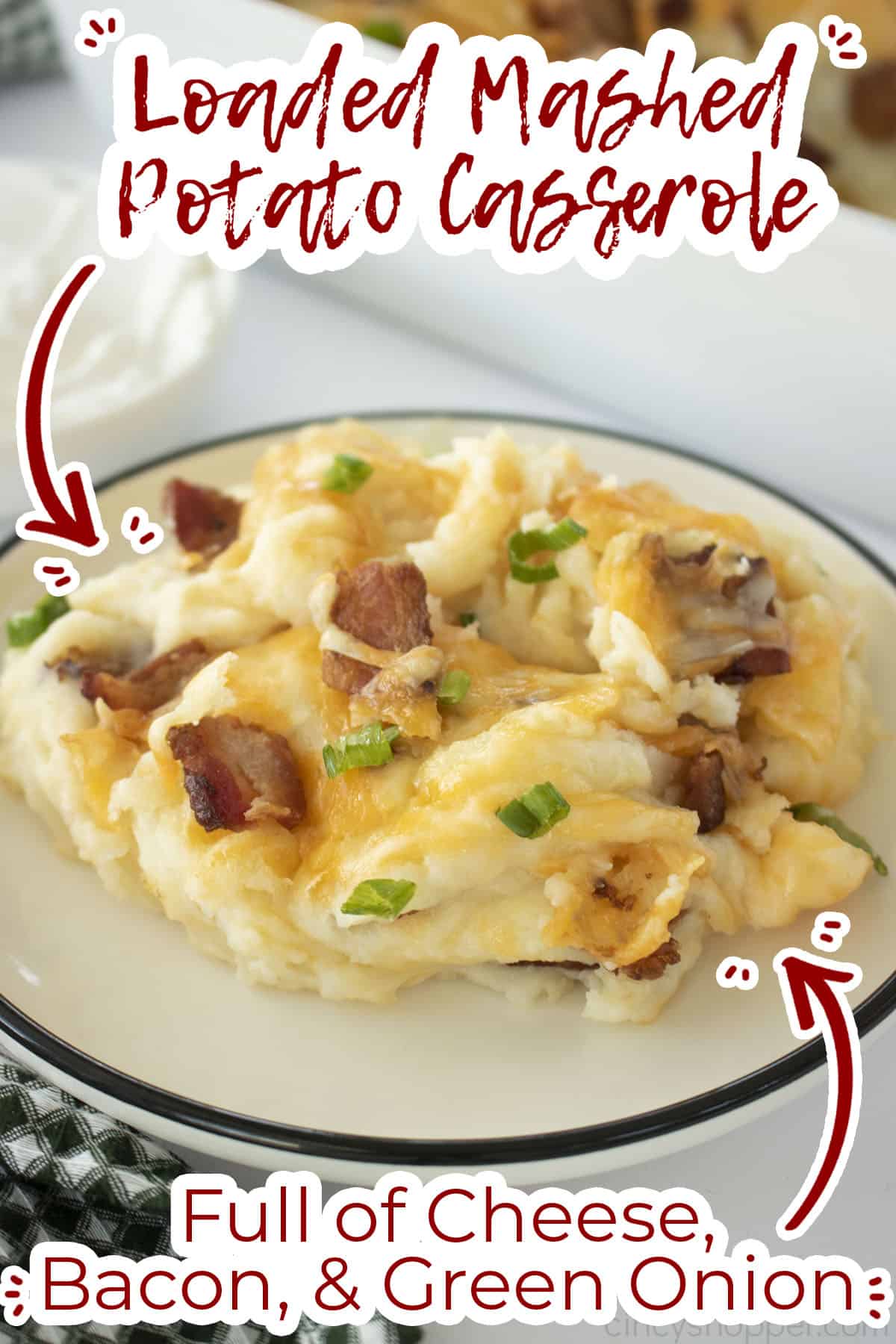 Loaded mashed potato casserole on a plate with text on image full of cheese, bacon and green onion. 