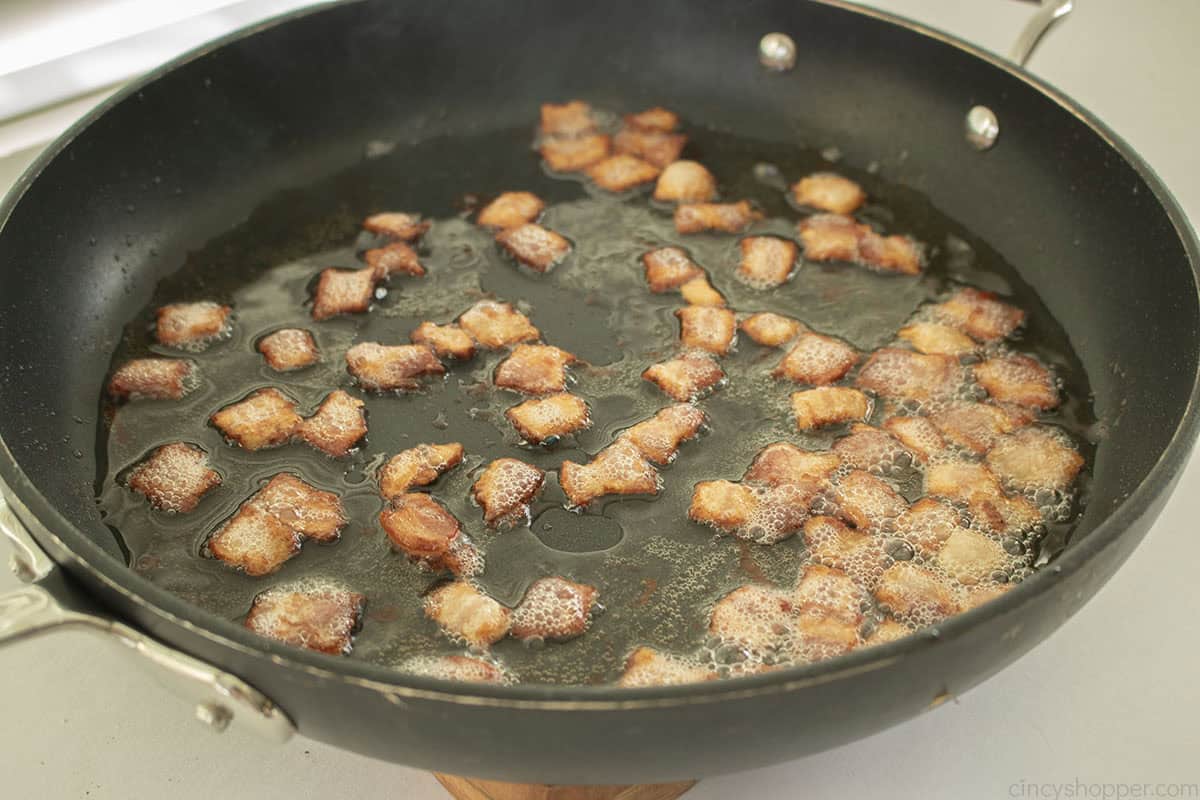 Bacon bits in a dark frying pan.