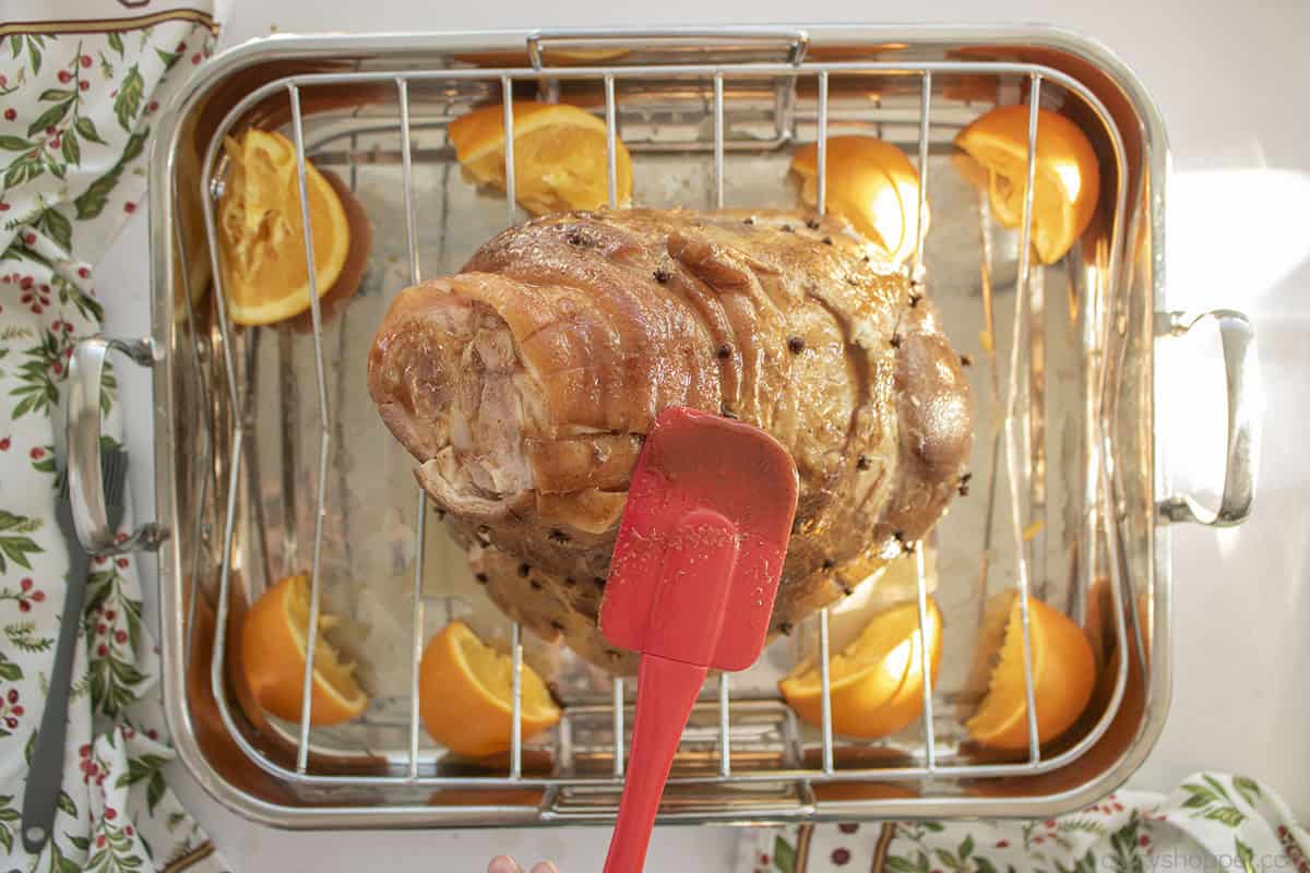 Adding maple glaze to uncooked ham.