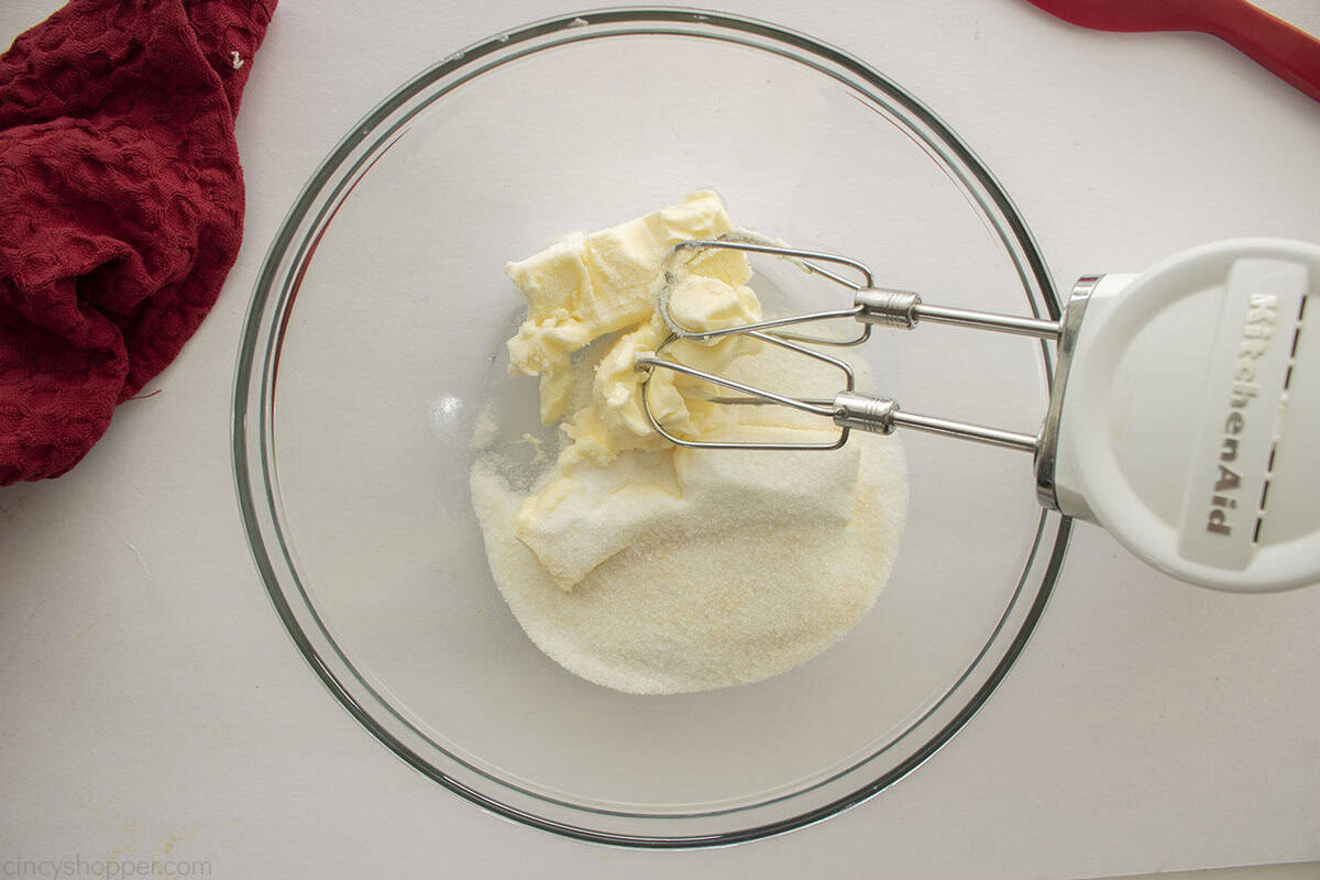 Clear mixing bowl with butter and sugar and hand mixer.