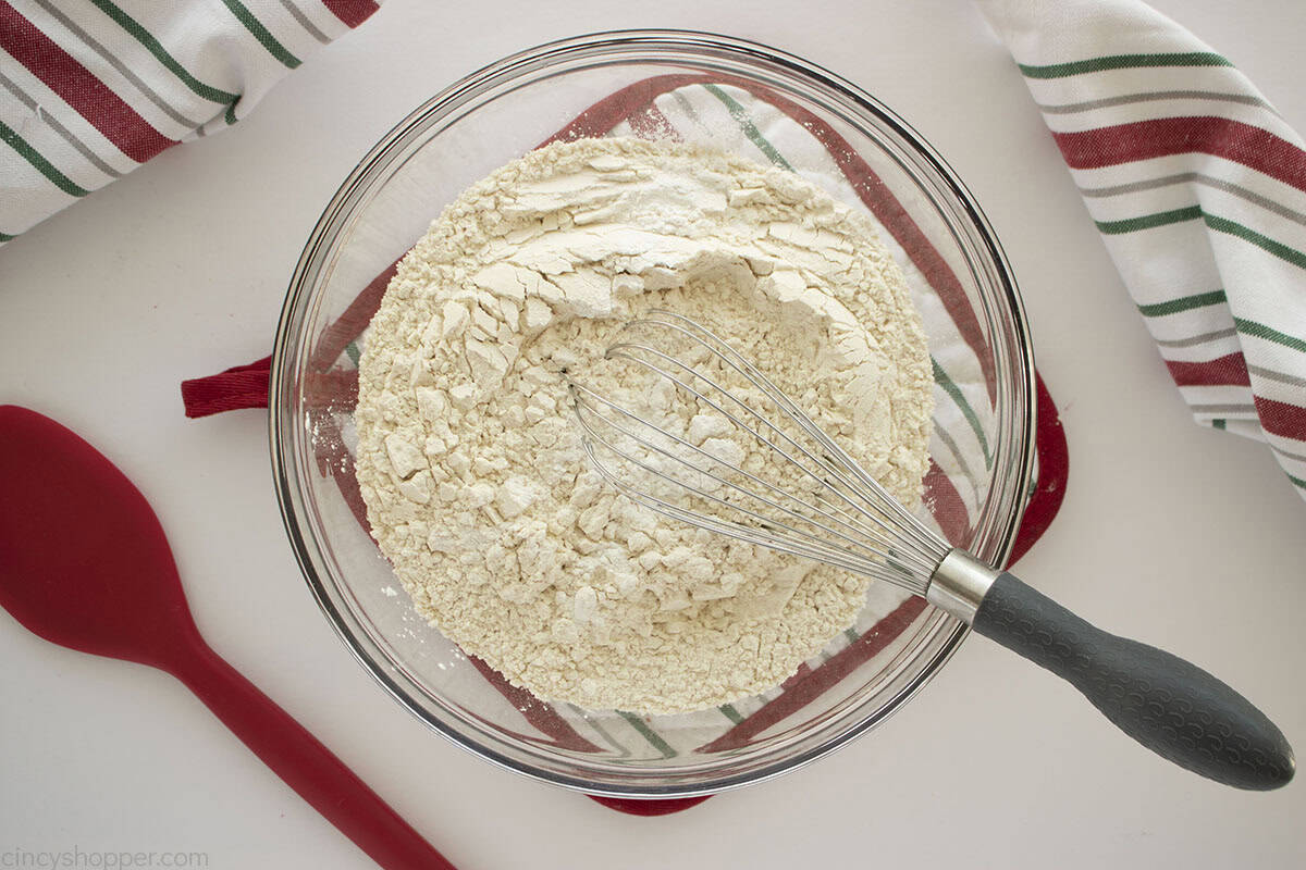 Flour and baking powder in a clear mixing bowl with whisk.