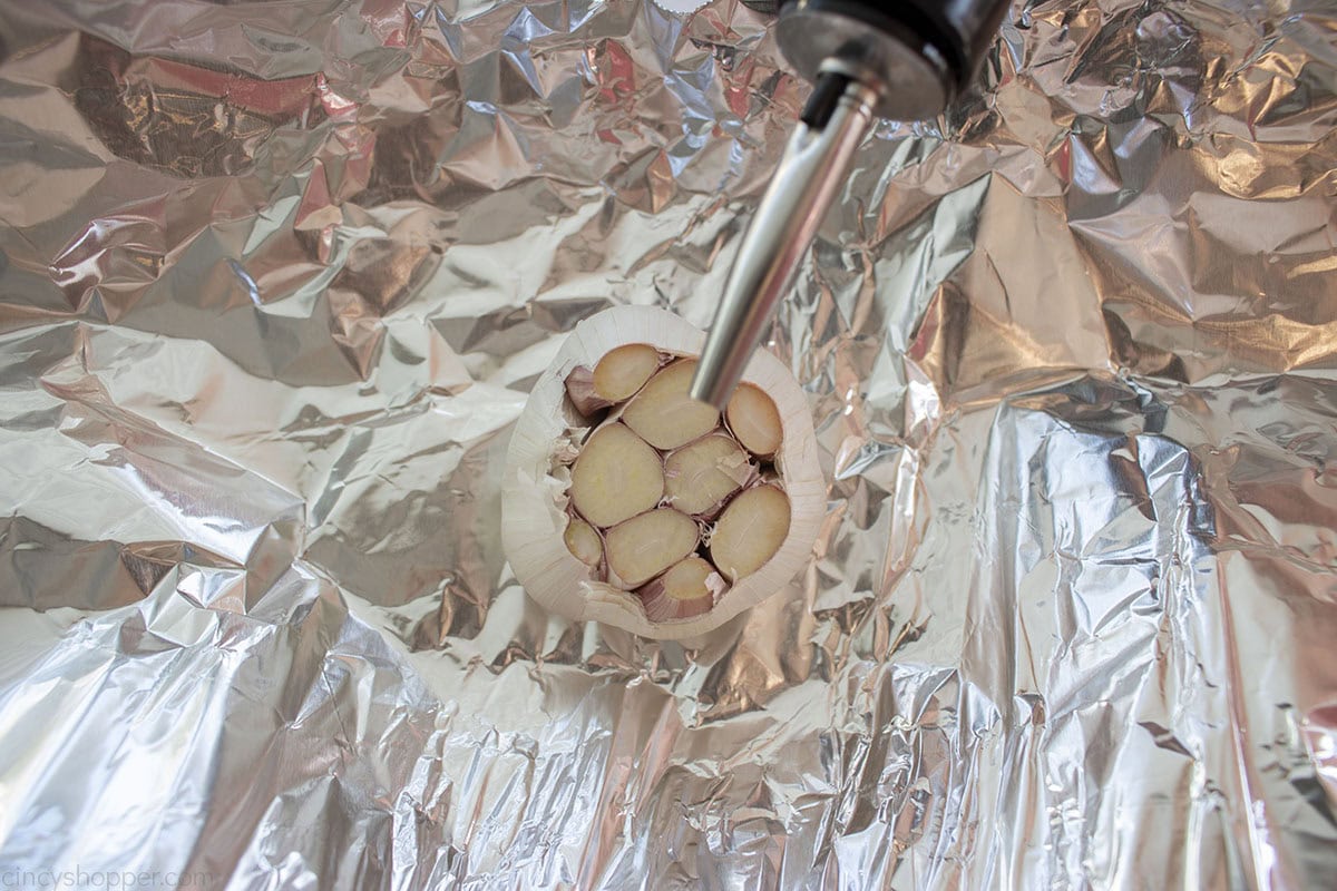 Putting olive oil on a clove of fresh garlic.