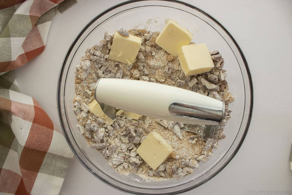 Ingredients for pecan topping inn a mixing bowl with a pastry cutter.