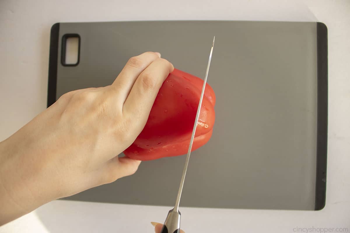 Cutting the bottom of a red pepper with a knife for turkey face.