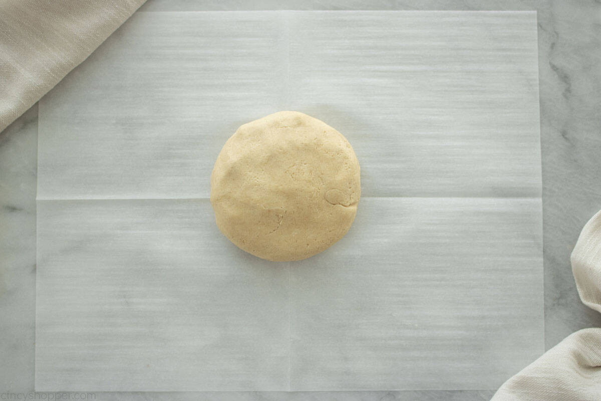 Cookie dough ball on parchment sheet.