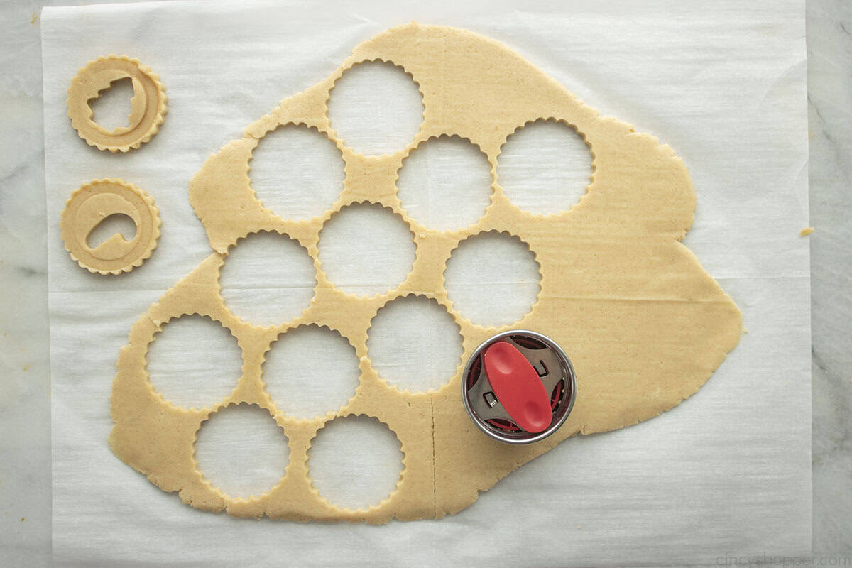 Linzer cookie cutter with sheet of cookie dough with cutouts.