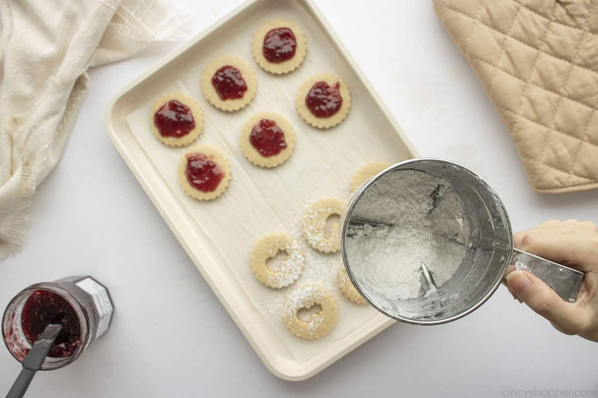 Sifter adding powdered sugar to cookie tops