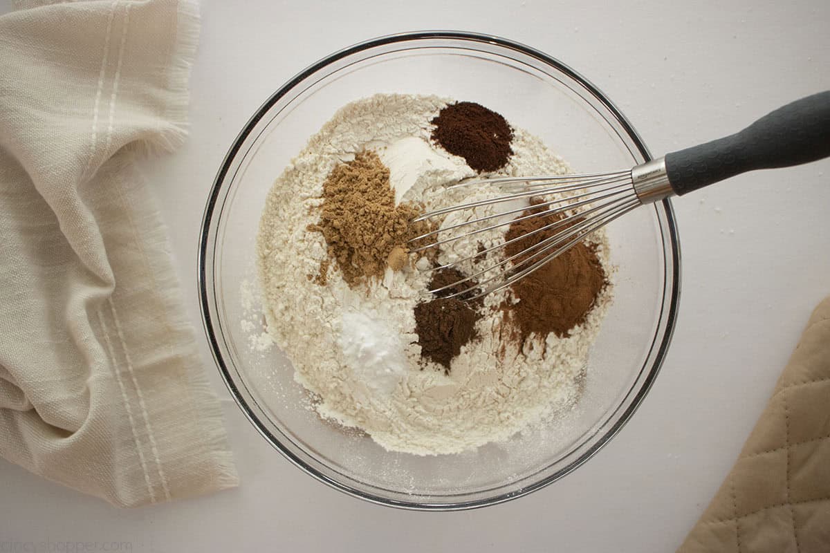 Dry cookie ingredients in a clear mixing bowl with a whisk.