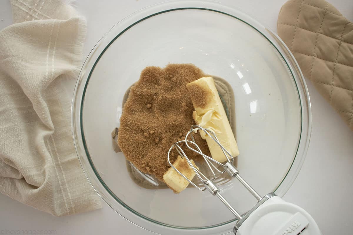 Butter and brown sugar in a mixing bowl with a hand mixer.