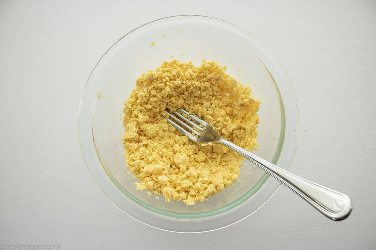 Egg yolks mashed in a bowl with a fork.