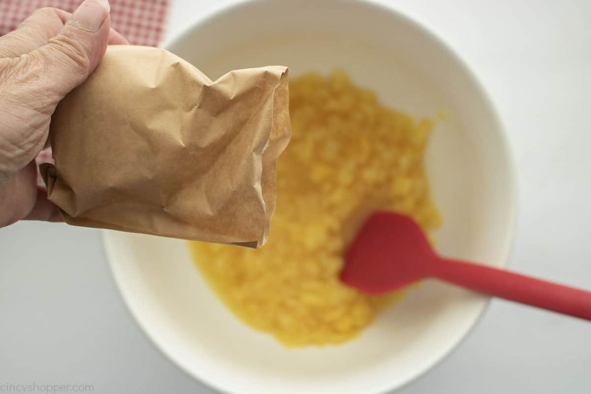 Adding pudding powder to crushed pineapple.