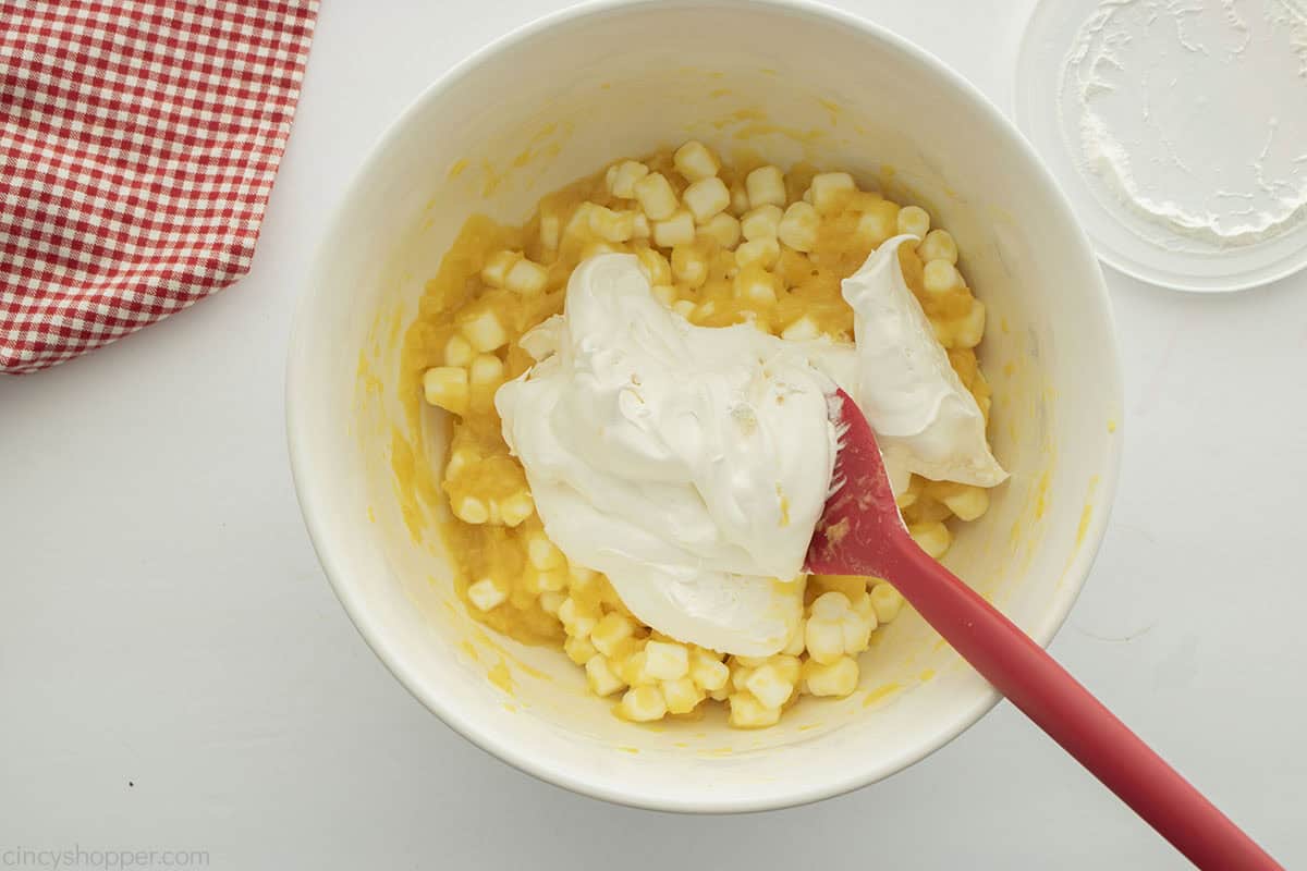 Adding whipped topping to the marshmallow mixture.