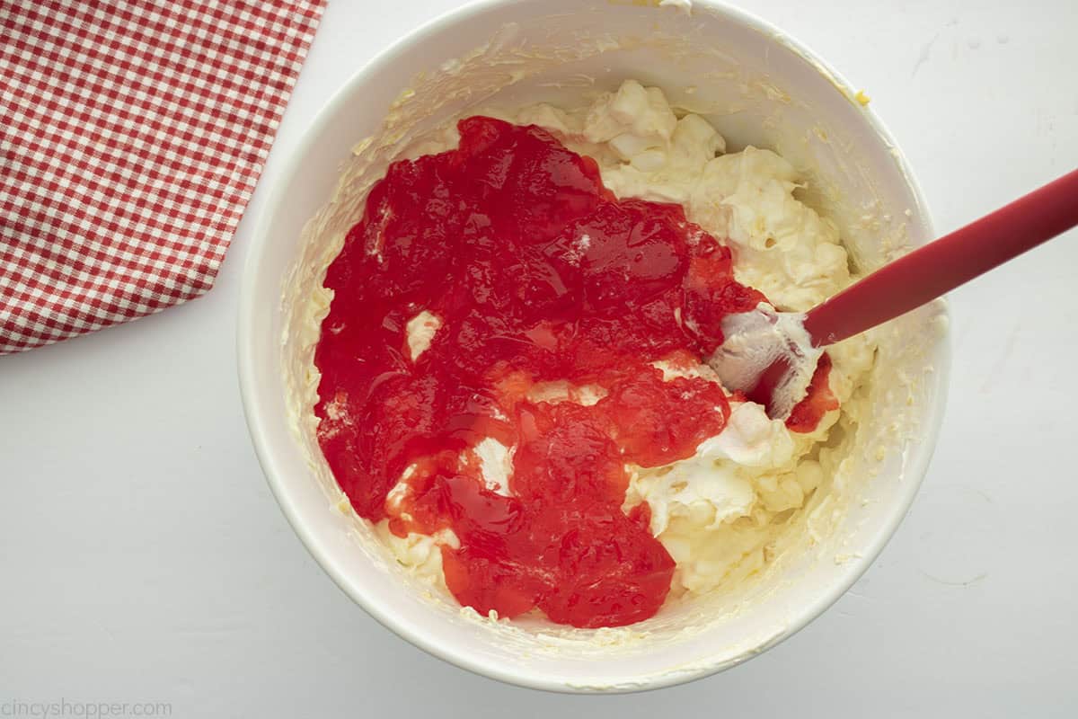 Adding strawberry jello to fluffy mixture.