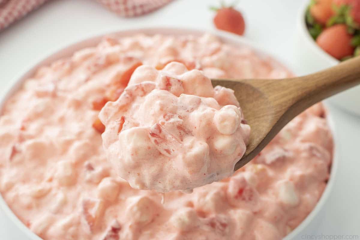 Old fashioned strawberry jello salad on a wooden spoon.