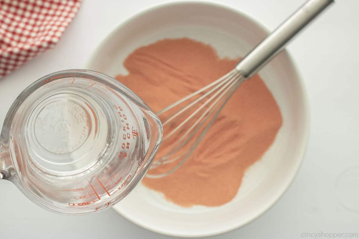 Pouring water into a bowl with powdered Jello