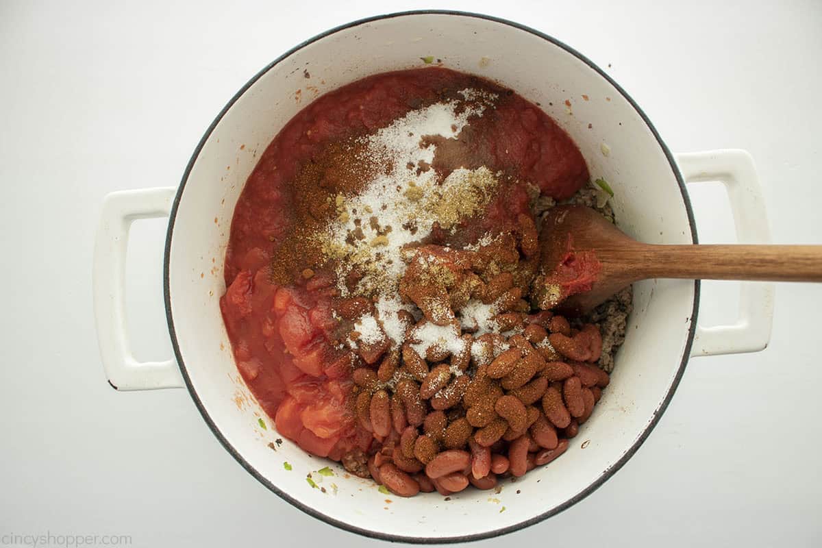 Tomatoes, beans and spices added to chili pot.