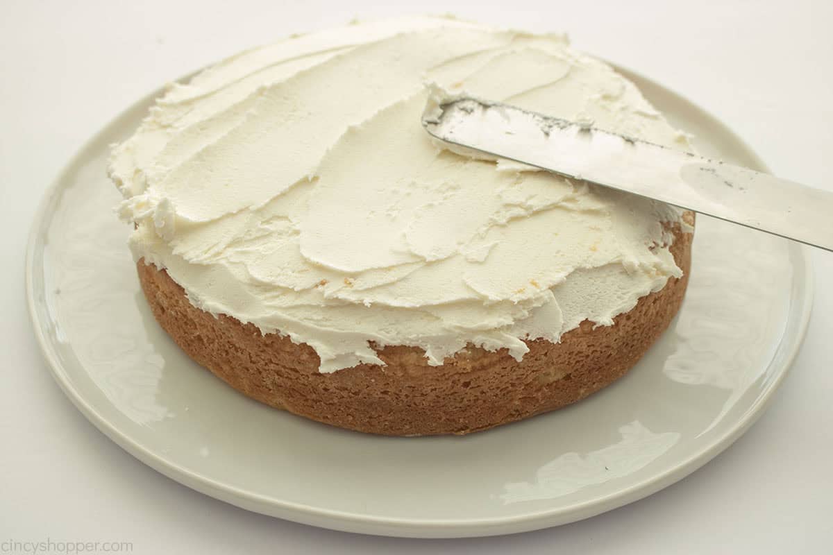 Adding frosting to white cake.