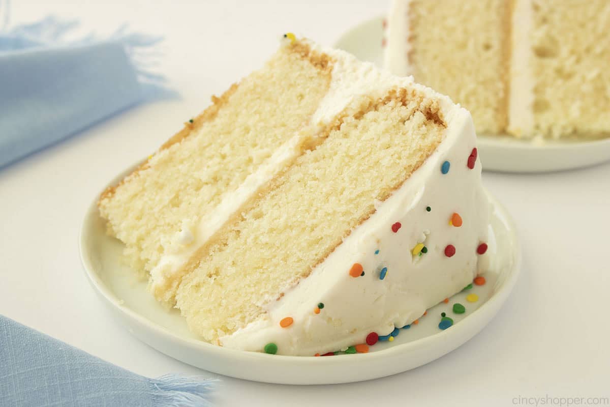 Slice of frosted white cake on a plate.