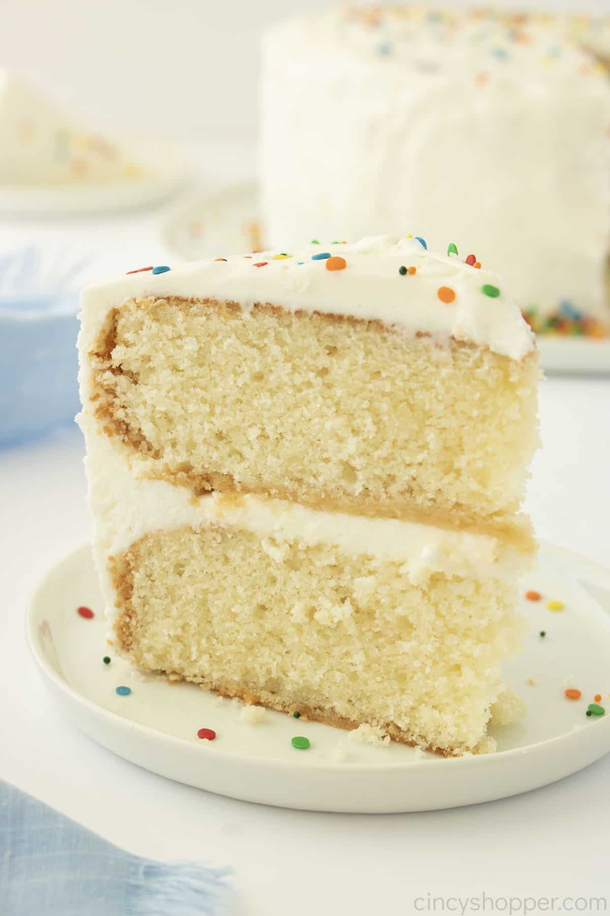 Layered White Cake with vanilla frosting on a white plate.