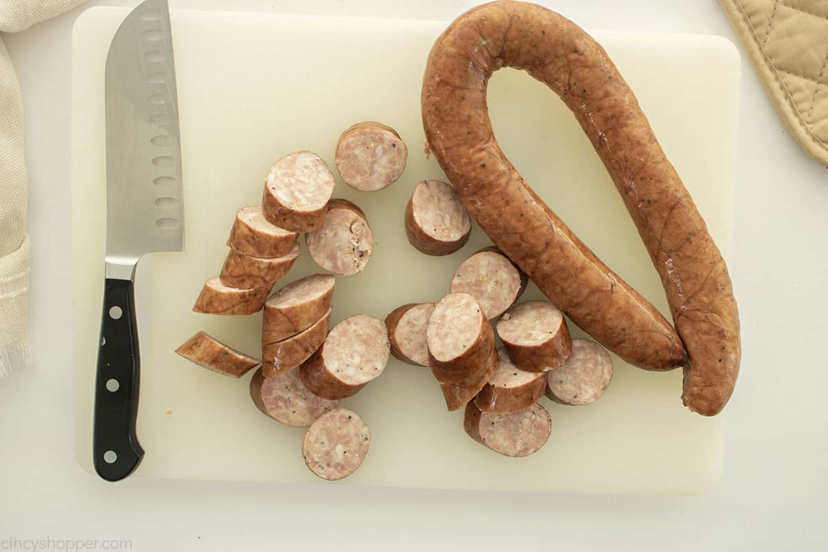 Sliced sausage on a cutting board with knife.