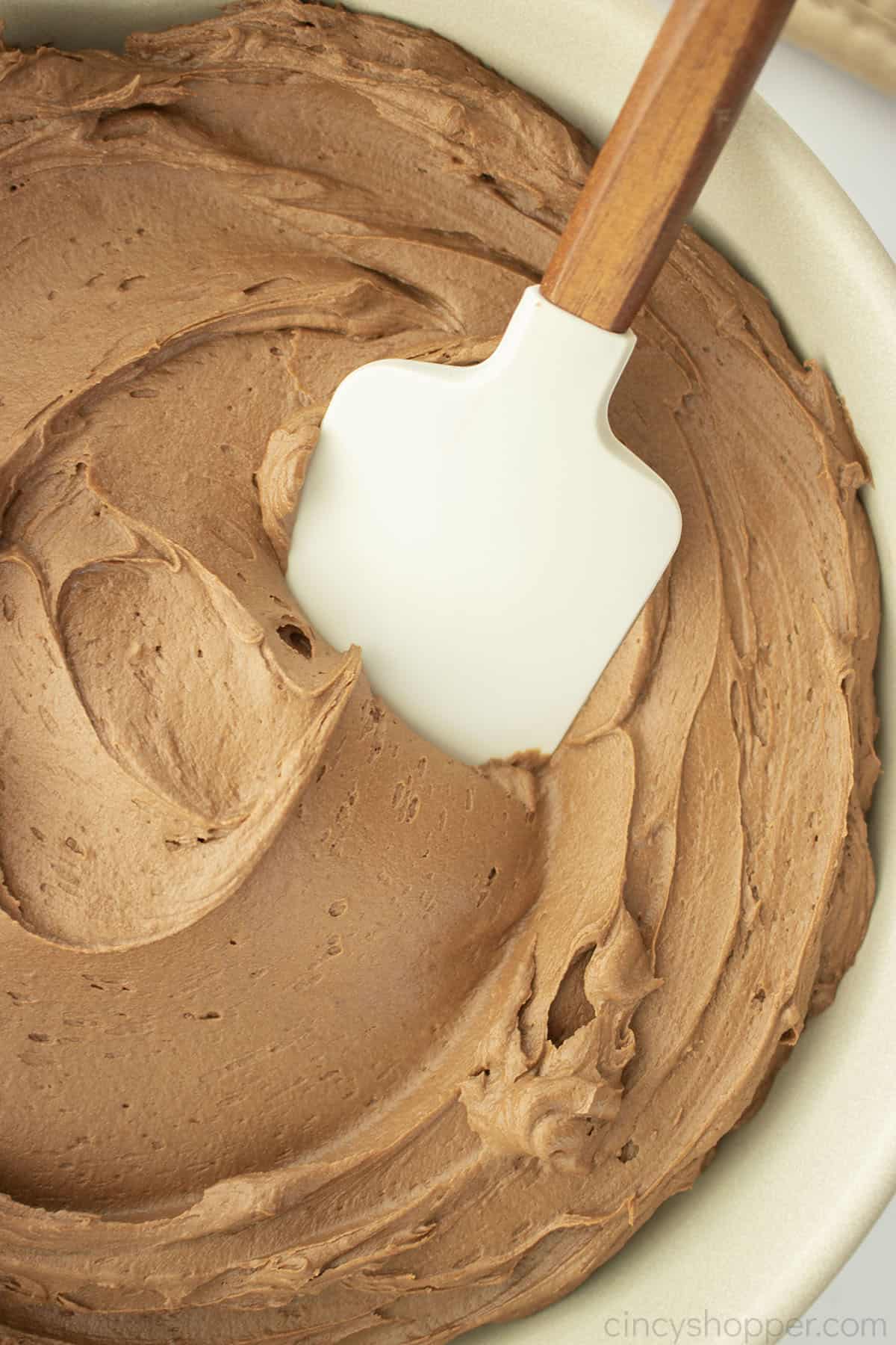 Closeup of spatula with chocolate frosting.