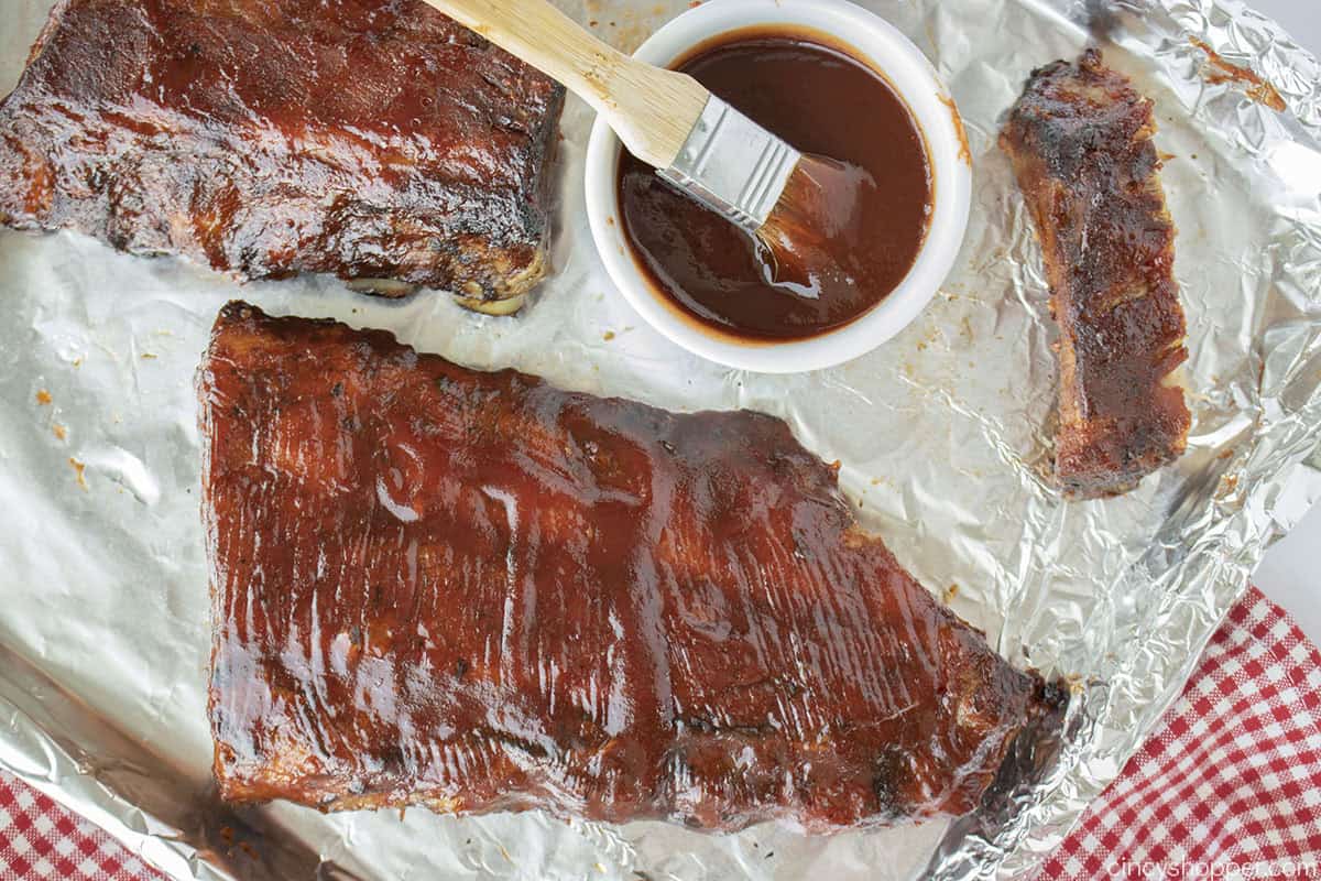 Slab of oven cooked ribs on a foil lined pan.